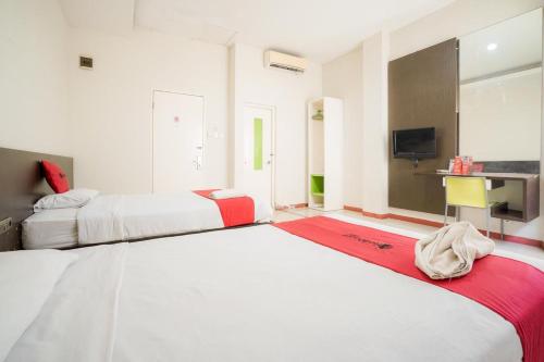 a bedroom with two beds and a television in it at RedDoorz near Pantai Pede in Labuan Bajo