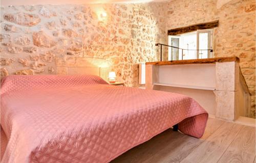 1 dormitorio con cama rosa y pared de piedra en Amazing Home In Goudargues With Kitchen, en Goudargues