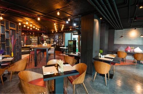 a restaurant with tables and chairs and a bar at Maitria Mode Sukhumvit 15 Bangkok - A Chatrium Collection in Bangkok