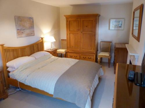 a bedroom with a bed and a dresser and a desk at Chareside Cottage in Corbridge