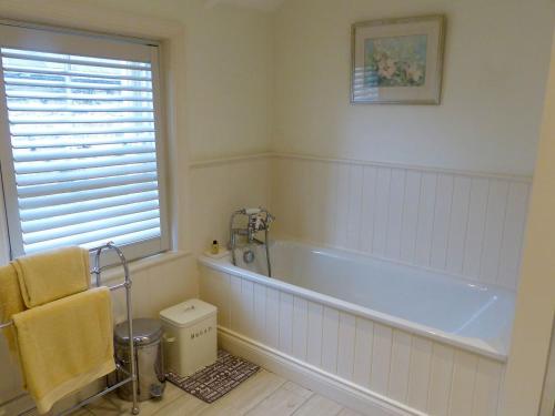 a bathroom with a tub and a chair and a window at Chareside Cottage in Corbridge