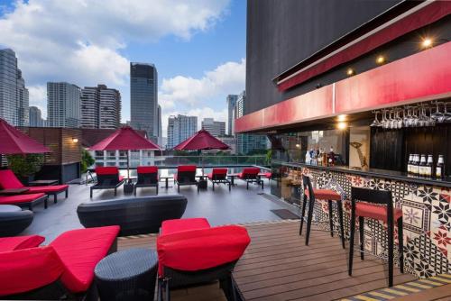 a rooftop bar with red chairs and tables on a building at Maitria Mode Sukhumvit 15 Bangkok - A Chatrium Collection in Bangkok