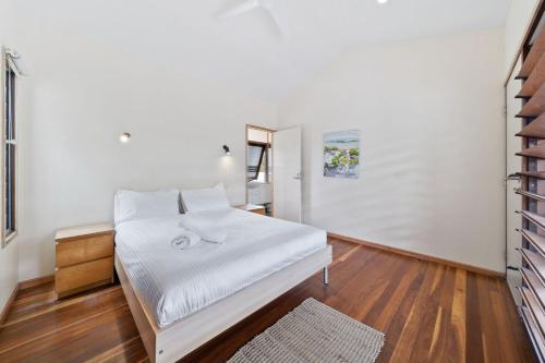 a bedroom with a bed with white sheets and a mirror at Laguna in Point Lookout