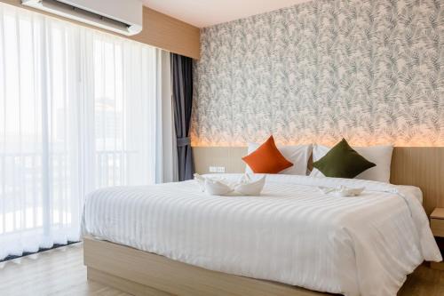 a bedroom with a white bed and a large window at ONE Hotel in Pathum Thani