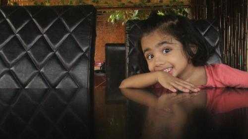 a little girl sitting at a table in a chair at Chanaka Eco Camp ( Adventure Assam ) in Pakariāmukh