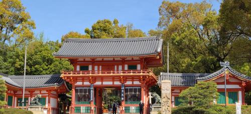 a red building with a black roof and trees at ibis Styles Kyoto Shijo in Kyoto