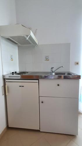 a white kitchen with a sink and a stove at Blue Bay Apartment in Chania