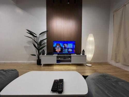 sala de estar con TV y mando a distancia en Mujito 8PAX NearTC, DinosaurLand, PoolTable, PS4, en Kuantan