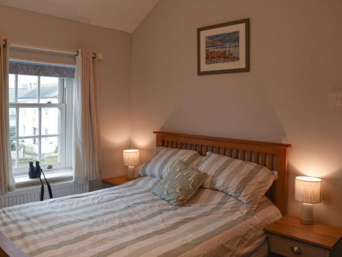a bedroom with a bed with two lamps and a window at Princessa Cottage in Bembridge
