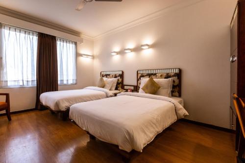 two beds in a hotel room with white sheets at 3 BY OYO Nami Residency Ahmedabad in Ahmedabad