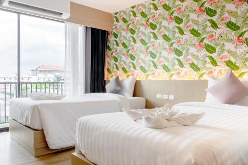 duas camas num quarto de hotel com uma parede floral em ONE Hotel em Pathum Thani