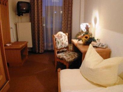 a living room with a table and a chair and a desk at Hotel Restaurant Hassia in Frielendorf