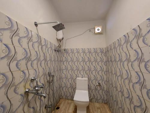 a bathroom with a toilet and a wall with swirl wallpaper at Megha Beach Resort - Sea View in Mandarmoni