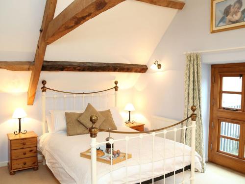 a bedroom with a white bed and wooden beams at Stanley Barn in Stonehouse