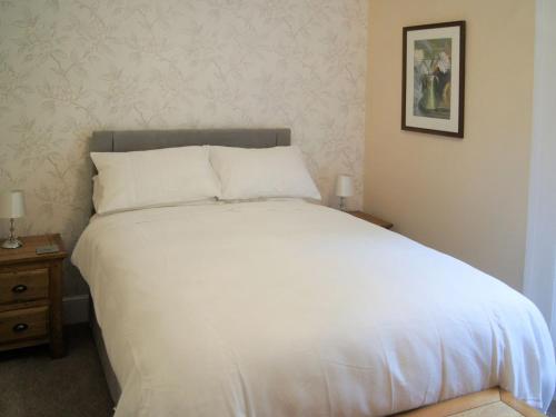 a bedroom with a large white bed with a night stand at Squirrels Retreat - Uk30821 in Braithwaite