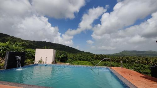 a swimming pool with a view of a mountain at Rajput Farm in Alibaug