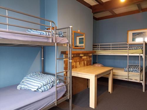 a room with bunk beds and a table and a desk at Rotorua Central Backpackers in Rotorua