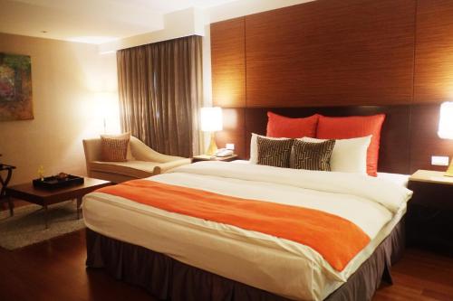 een hotelkamer met een groot bed en een stoel bij Aqua Bella Hotel in Taipei