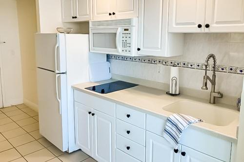 a kitchen with white cabinets and a white refrigerator at Daytona Beach Resort 805 in Daytona Beach