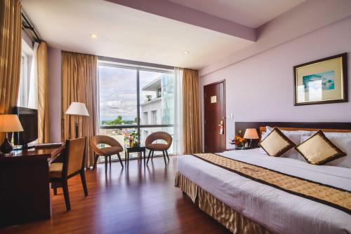 a hotel room with a bed and a desk and a window at Mondial Hotel Hue in Hue