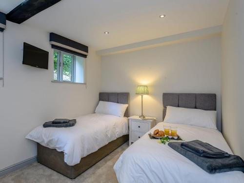 a bedroom with two beds and a tv on the wall at Bluestone Cottage in Welton le Wold