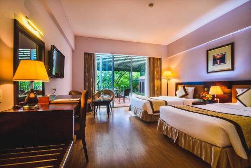 a hotel room with two beds and a desk at Mondial Hotel Hue in Hue