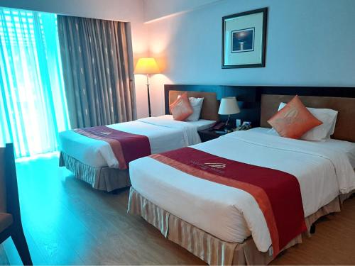 a hotel room with two beds and a window at Mondial Hotel Hue in Hue