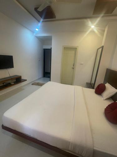 a large white bed in a room with a tv at DC comforts in Chikmagalūr
