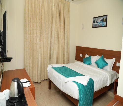a bedroom with a bed and a desk and a window at Hotel Royal Chola in Kanchipuram
