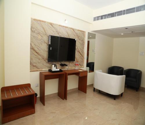 a room with a desk with a television and a chair at Hotel Royal Chola in Kanchipuram
