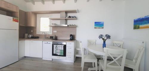 una cocina con armarios blancos y una mesa con sillas. en ALBA OCEAN VIEW LUXURY RESIDENCE en Néa Ankhíalos
