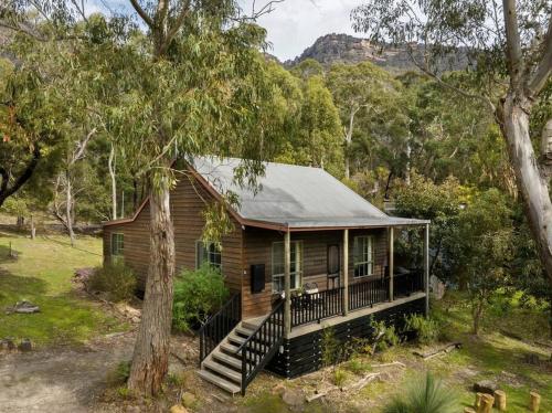 a log cabin in the woods with a tree at Country Lane Cottage in Halls Gap