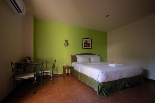 a bedroom with a bed and a green wall at Opey De Place in Pattaya