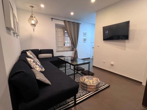 a living room with a black couch and a tv at Sueños de la Alhambra in Granada