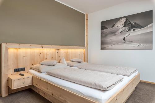 a large bed in a bedroom with a picture on the wall at Hohenegg Apartment Karolina in Campolasta