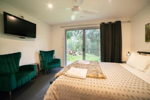 大廳峽的住宿－拉庫納度假屋，一间卧室配有一张床和两张绿色椅子