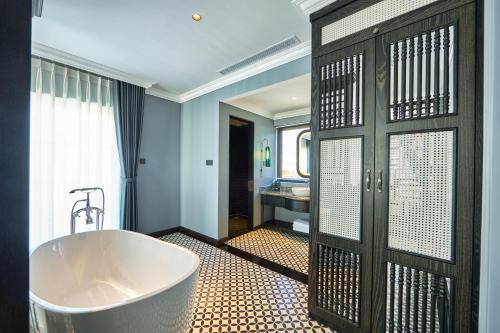 a bathroom with a large bath tub next to a door at Hôtel D’Melin in Vung Tau