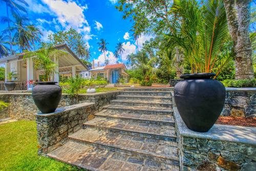 a home with two large vases on a stone path at The Niche Hikkaduwa - 10 minutes to the beach in Hikkaduwa
