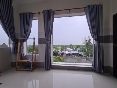 Zimmer mit einem großen Fenster und blauen Vorhängen in der Unterkunft Khách sạn Hoàng Mai in Ấp Thới Thuận (4)