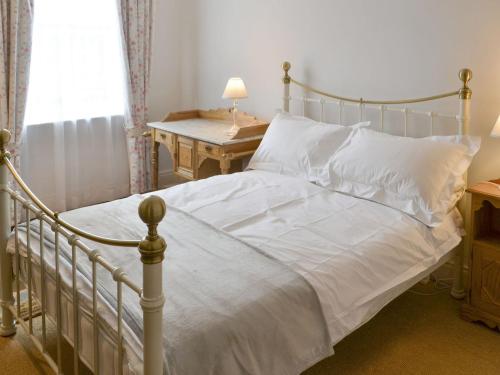 a bedroom with a bed with white sheets and a table at Drovers in Morpeth
