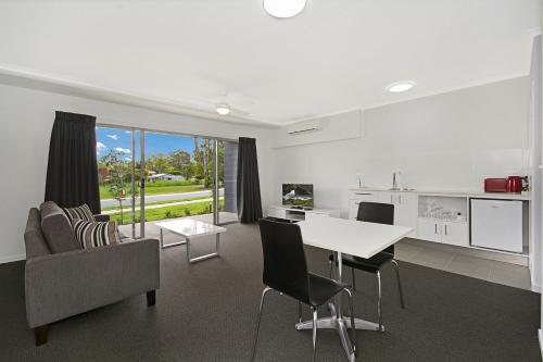 a kitchen and living room with a table and chairs at Cooroy Luxury Motel Apartments in Cooroy