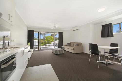 a kitchen and living room with a table and chairs at Cooroy Luxury Motel Apartments in Cooroy
