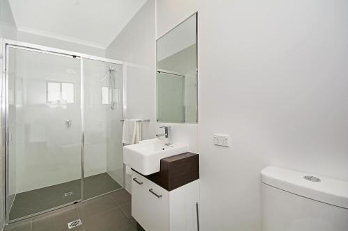 Cooroy Luxury Motel Apartments في Cooroy: حمام أبيض مع حوض ودش