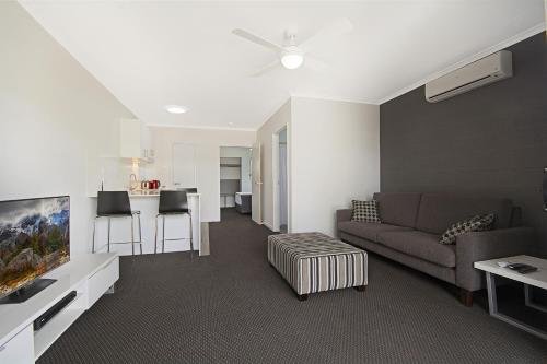 a living room with a couch and a kitchen at Cooroy Luxury Motel Apartments in Cooroy