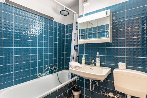 uma casa de banho em azulejos azuis com um lavatório e uma banheira em Fewo Luzia em Schönwald