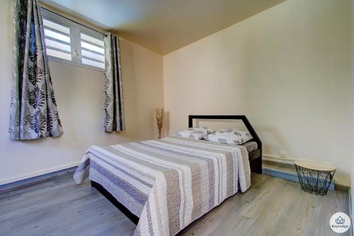 1 dormitorio con 1 cama con manta a rayas y ventana en Mauricia - Maison - 77m2 - Saint-Benoit, en Saint-François