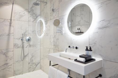 a white bathroom with a sink and a mirror at TORTUE Hamburg in Hamburg