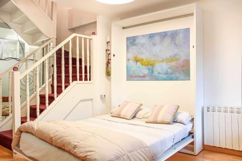 a white room with a bed and a staircase at Casa La Hiedra dúplex independiente jardín privado in Panticosa