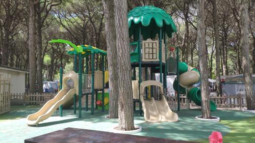 un parco giochi con scivolo in un parco alberato di MareBlue Mobilhomes & Caravans a Lido di Spina