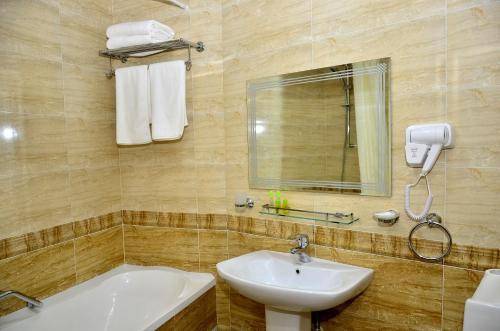 y baño con lavabo, espejo y bañera. en Hotel Diyora, en Samarkand